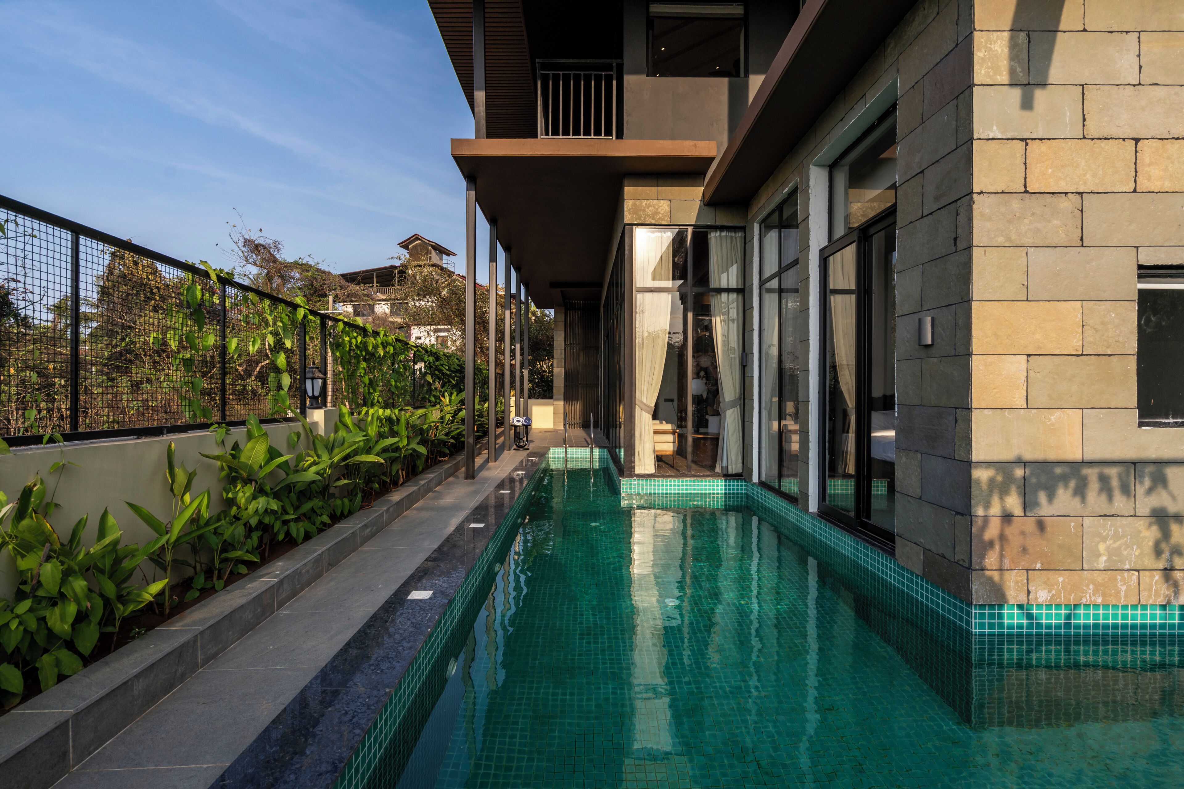 A swimming pool with a clear view of the adjacent building's exterior, including a balcony and large windows.