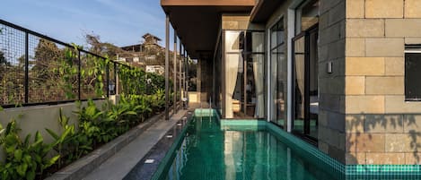 A swimming pool with a clear view of the adjacent building's exterior, including a balcony and large windows.