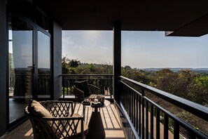 Un balcón con vistas al paisaje, una mesa con objetos y una silla de mimbre.