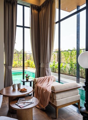 A room with a large window, a pool, and a seating area with a table and a chair. - Staymaster Timber Ridge - 4BR with Pool (Sangolda)