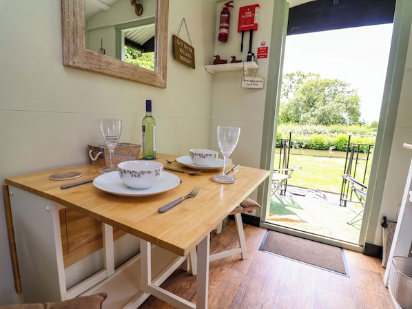 A dining table with plates, glasses, and cutlery, a bottle of wine, a mirror, and a fire extinguisher. - Hop To It (Whitchurch)