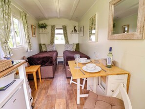 A cozy room with two beds, a dining table, and a mirror. - Hop To It (Whitchurch)
