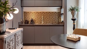 Eine moderne Küche mit einem gemusterten Rückwand, einer Kaffeemaschine und einem Essbereich mit einem runden Tisch.