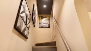 Una escala amb barana que condueix a un vestíbul amb obra d'art a les parets.