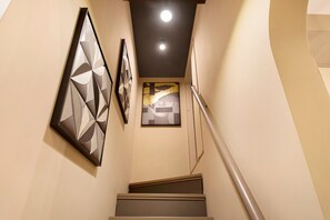 A staircase with a handrail, leading to a landing with artwork on the walls. - Archs Apartment - Deluxe in Catania (Catania)
