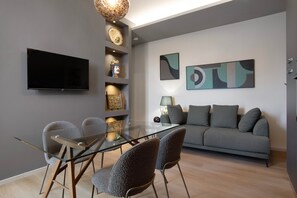 A modern living room with a glass dining table, grey sofa, and abstract wall art. - Archs Apartment - Deluxe in Catania (Catania)