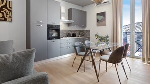Una cuina moderna amb armaris grisos, una taula de dinar de vidre i vista a l'exterior.