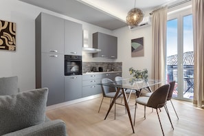 A modern kitchen with grey cabinets, a glass dining table, and a view of the outside. - Archs Apartment - Deluxe in Catania (Catania)