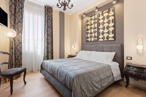 A bedroom with a large bed, a chair, a desk, and a chandelier. - Archs Apartment - Deluxe in Catania (Catania)
