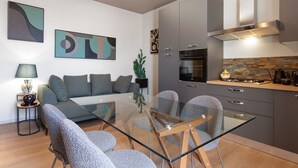Una cuina moderna amb armaris grisos, un forn de mur i una placa de gas.