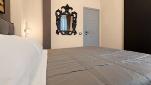 Habitació d'hotel amb un llit gran, un mirall fixat a la paret, una porta i un lluminària.