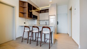 A modern kitchen with white cabinetry, a marble countertop, and three wooden bar stools. - w Deluxe 2BR w Balcony View in San Francisco (Panama City)