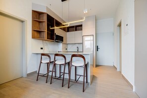 A modern kitchen with white cabinetry, a marble countertop, and three wooden bar stools. - w Deluxe 2BR w Balcony View in San Francisco (Panama City)