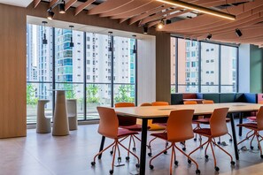 A modern conference room with a large table and orange chairs, large windows with a view of high-rise buildings, and a wooden ceiling with track lighting. - w Deluxe 2BR w Balcony View in San Francisco (Panama City)