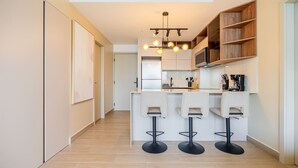 A modern kitchen with a central island, bar stools, and built-in wooden shelves. - w Amazing 2BR w Balcony AC in San Francisco (Panama City)