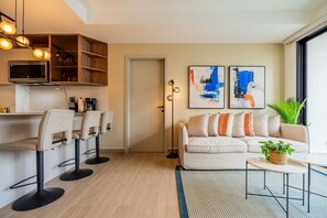 Ein modernes Wohnzimmer mit einer Couch, Sesseln, einem Couchtisch und abstrakter Kunst an der Wand.