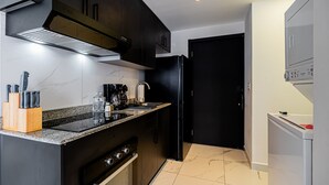 Eine moderne Küche mit dunklen Schränken, einer Edelstahl-Dunstabzugshaube, einem eingebauten Backofen und einem schwarzen Kühlschrank.