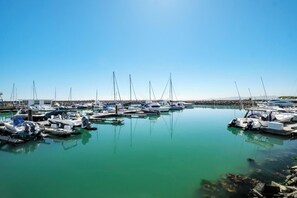 Ein Yachthafen mit mehreren vertäuten Booten, ruhigem Wasser und wolkenlosem Himmel.