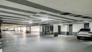 En parkeringsgarage med flere etager, beton gulve og vægge, mange parkeringspladser og et par biler.