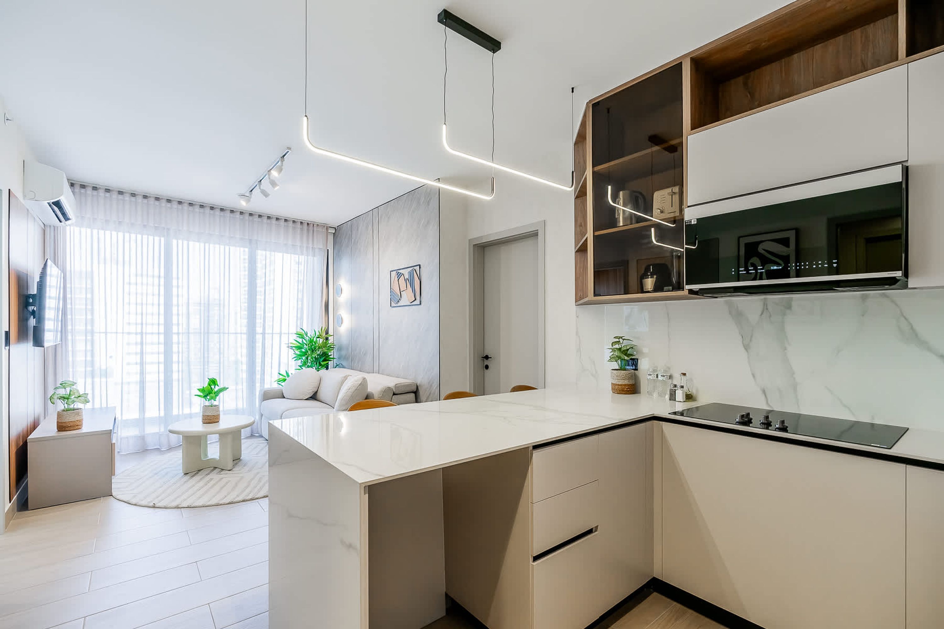 A modern kitchen with a marble countertop, built-in oven, and pendant lighting.