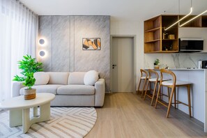 A modern living room with a sofa, a small table with a plant, and a kitchen area with bar stools. - w Upscale 2BR w Balcony AC in San Francisco (Panama City)
