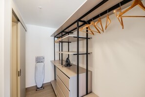 A modern closet with wooden hangers, a built-in ironing board, and a minimalist design. - w Upscale 2BR w Balcony AC in San Francisco (Panama City)