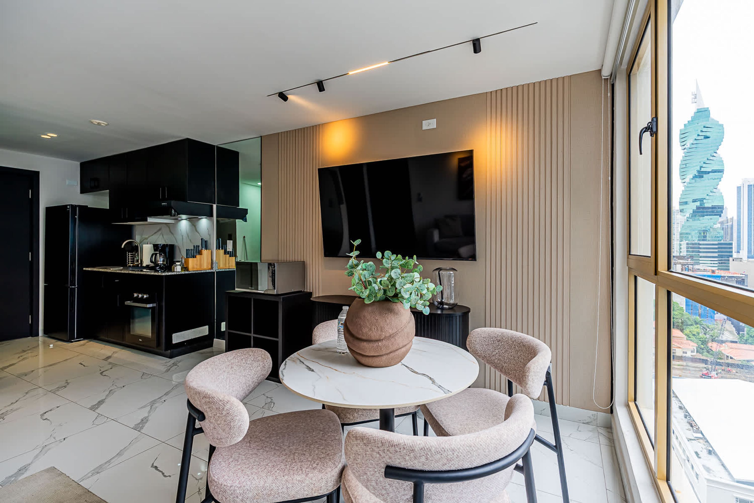 Una cucina moderna con mobili neri, un tavolo da pranzo con quattro sedie e un'ampia finestra con vista sulla città.
