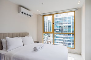 A hotel room with a large bed, a view of buildings, and an air conditioning unit. - w Polished 1BR Stay in Vibrant Obarrio (Panama City)