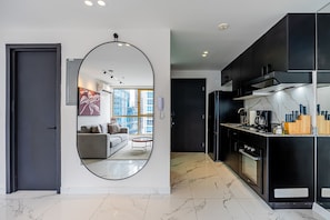 A modern kitchen with black cabinets, a marble countertop, and a large mirror. - w Polished 1BR Stay in Vibrant Obarrio (Panama City)