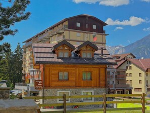 A multi-story hotel with a wooden facade, balconies, and a mountain backdrop. - The Clotes Hideaway - Steps From Chairlift (Sauze d'Oulx)