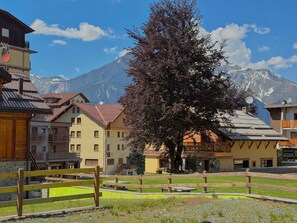 A mountain village with traditional buildings, a wooden fence, and a large tree in the foreground. - The Clotes Hideaway - Steps From Chairlift (Sauze d'Oulx)