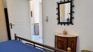 A room with a bed, a small vanity with a mirror, and a door leading to a kitchenette. - Vathia Tower - Stone Mani Heaven Near the Beach (East Mani)