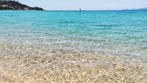 En lys og åben strand med synlige sandbanker under vandet.