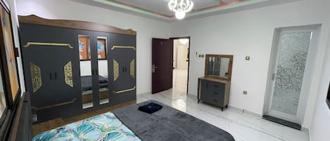 A bedroom with a bed, wardrobe, mirror, and a door with frosted glass.