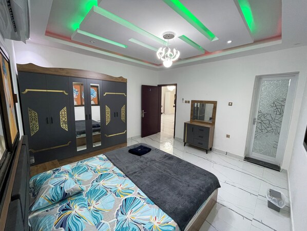 Un dormitorio con cama, armario, espejo y una puerta de cristal satinado.