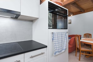 Una cocina compacta con encimera negra, armarios blancos y horno integrado.