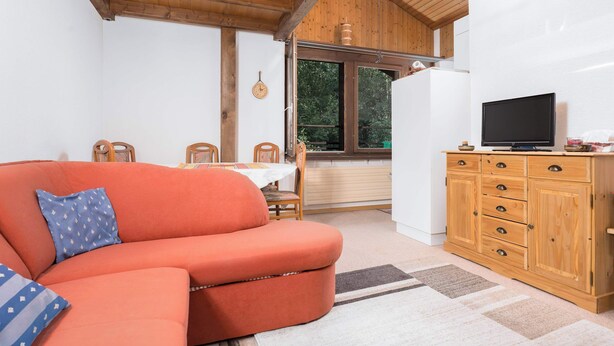 Un salón acogedor con un sofá, un televisor y un mueble de madera.
