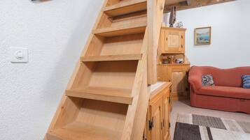 Eine Holztreppe mit Handlauf, ein rotes Sofa und ein Schrank mit einer Uhr.