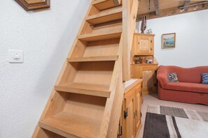 Una escala de fusta amb barana, un sofà vermell i un moble amb un rellotge.