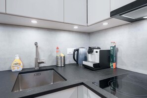 Cuina moderna amb un rentaplat, un búl, una màquina de cafè i una ampolla de crema corporal Elkos.