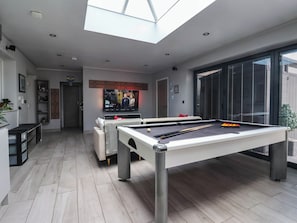 Una sala de estar moderna con mesa de billar, televisión y tragaluz.