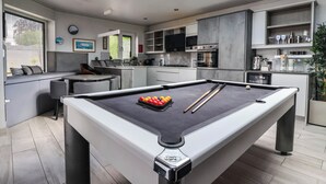 A modern kitchen with a built-in pool table, a dining area with a bench, and a large window providing natural light. - The Annexe (Shipley)