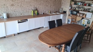 A kitchen with a wooden table and chairs, a white countertop, and a stone wall.