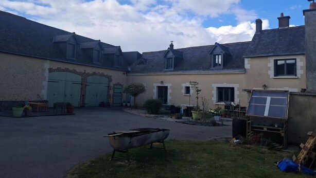 A courtyard with a boat, potted plants, and a building with a garage.