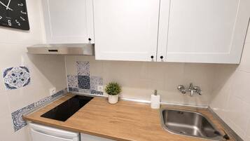 Een moderne keuken met witte kastjes, een zwarte quartz klok, een roestvrijstalen spoelbak en betegelde achterwand.