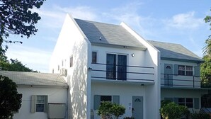 Un edifici de dues plantes amb teulada plana, un balcó i un camí d'accés de grava.
