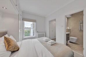 Ein modernes Hotelzimmer mit einem großen Bett, einem Fenster, einem Badezimmer und Blick auf die Stadt.