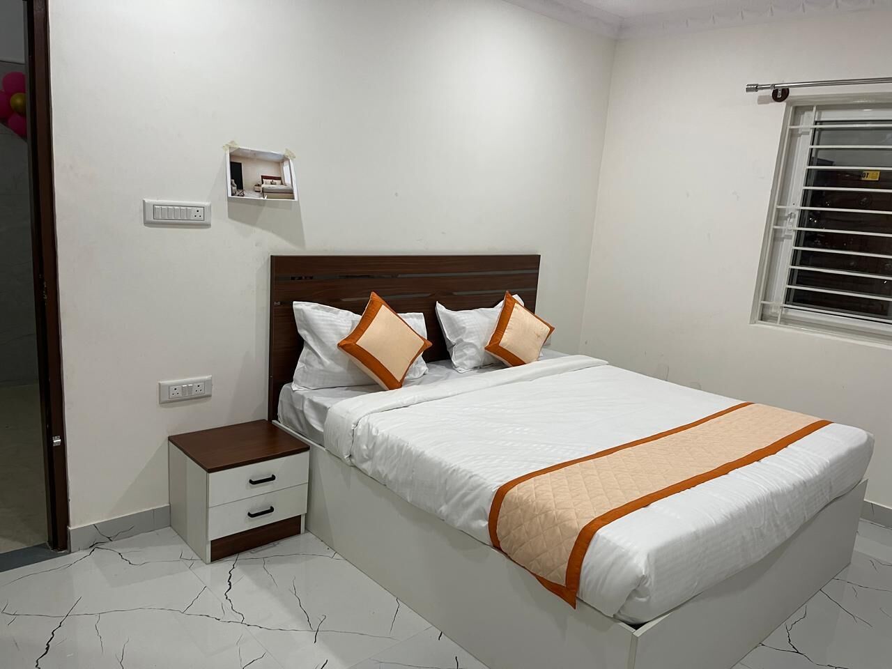 A bedroom with a bed, bedside table, and a window with blinds.