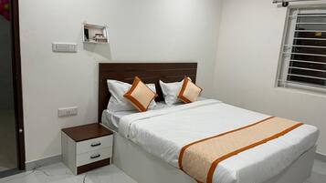 A bedroom with a bed, bedside table, and a window with blinds.