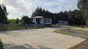 A small, single-story building with a fenced yard, surrounded by trees.
